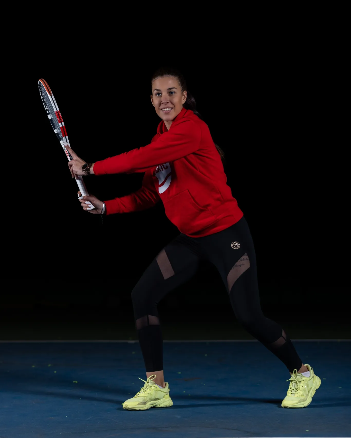 Ana Stojacic preparing a backhand on a blue tennis court
